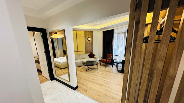 A modern hotel room with a marble floor, a bed, a sofa, a dining table, and a large mirror. - Rose Point Residence (Istanbul)