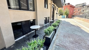 A modern outdoor seating area with a table and chairs, surrounded by planters with greenery. - Rose Point Residence (Istanbul)