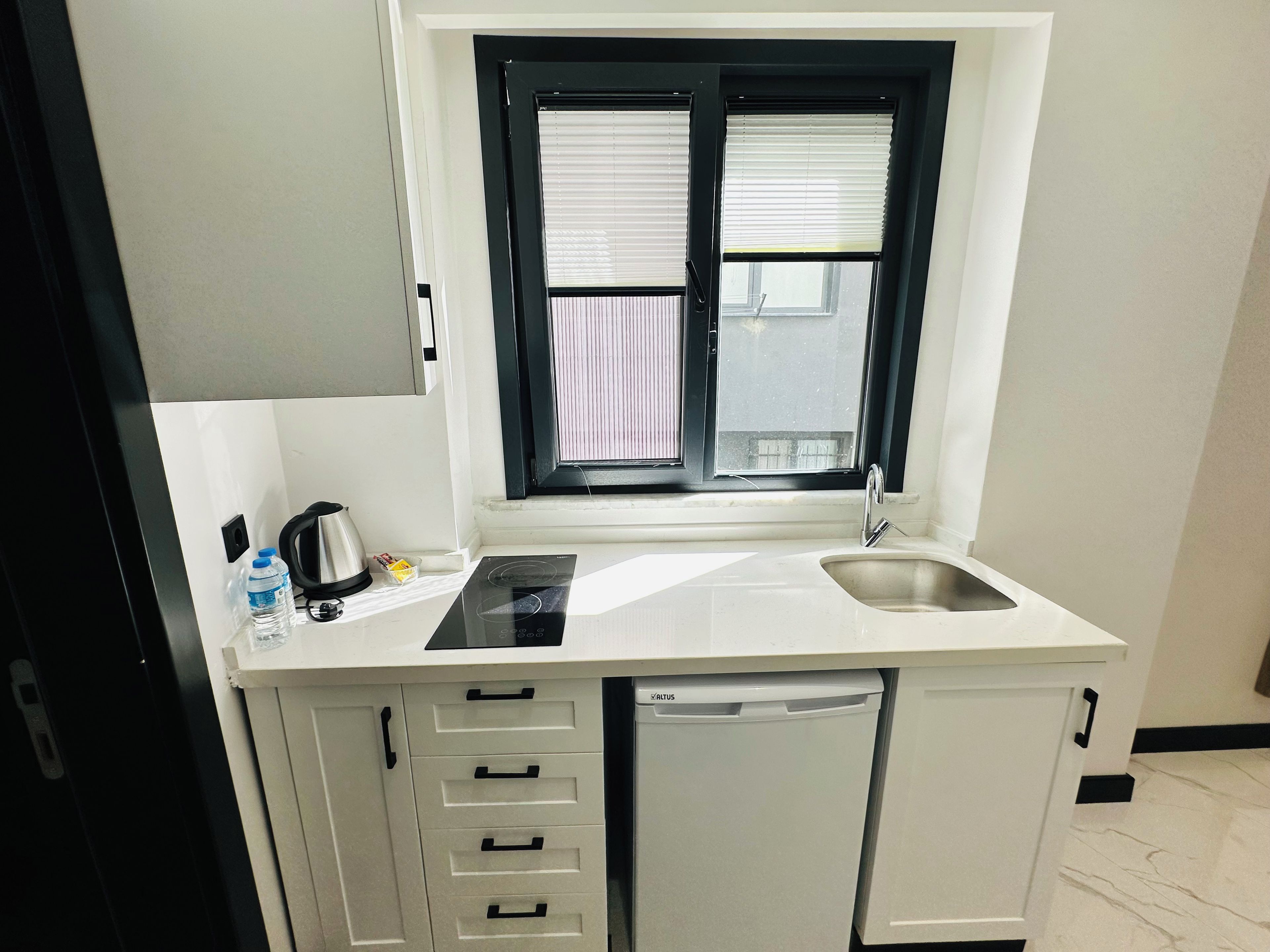 A compact kitchenette with a built-in stove, a sink, and a dishwasher.