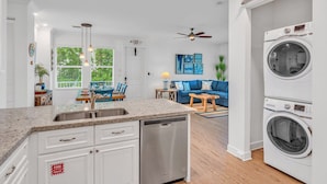 A modern kitchen with a dishwasher, a dining area with a table and chairs, a living room with a blue sofa, and a built-in washer and dryer. - P88 -  New on the rental market! 3 bedroom, 2 bath with private pool and 50 feet of dockage (Marathon)