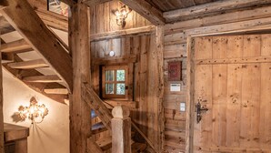 Un escalier en bois mène à une pièce dotée d’une grande porte en bois et d’une petite fenêtre.