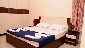 A neatly made bed with a blue and white bedspread, white pillows, and a decorative towel arrangement. - Sucasa Homes (Hyderabad)