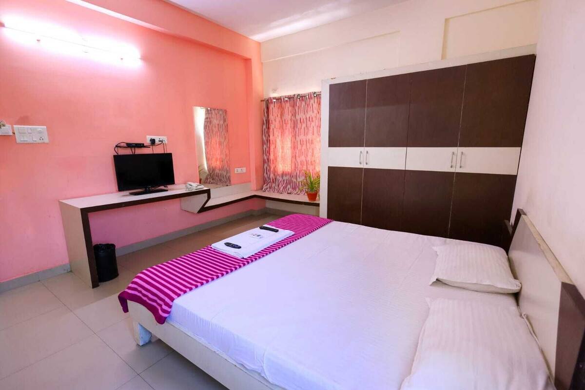 A bedroom with a bed, a desk, a television, and a wardrobe.