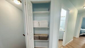 Ein begehbarer Kleiderschrank mit Regalen für gefaltete Kleidung und Aufbewahrungsboxen.