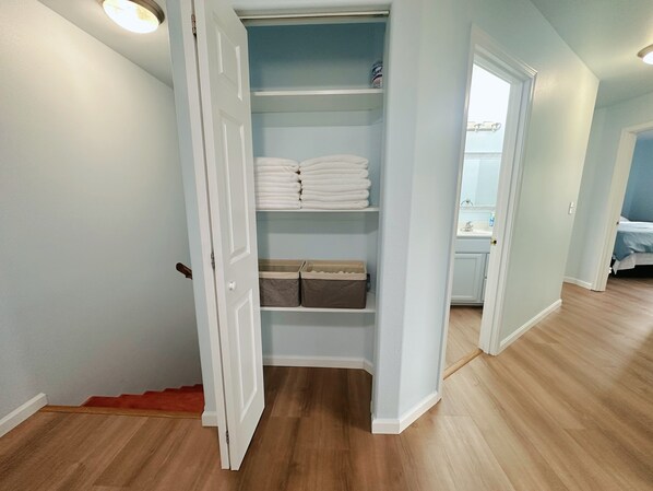 A walk-in closet with shelves for folded clothes and storage bins.