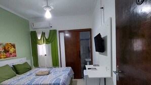 A bedroom with two beds, a desk, a TV, and a door marked with the number 6. - Pousada Nascimentos (Bertioga)