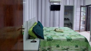 A bedroom with a bed, a TV mounted on the wall, and a door with a number plate. - Pousada Nascimentos (Bertioga)