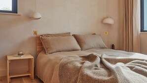 A bedroom with a bed, two bedside tables, a lamp, and a window with curtains.