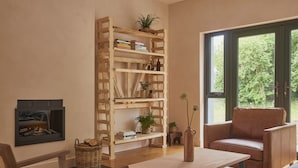 A cozy living room with a wooden bookshelf, a leather armchair, a small table, and a fireplace.