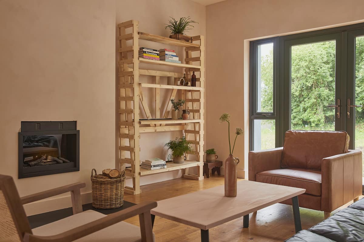A cozy living room with a wooden bookshelf, a leather armchair, a small table, and a fireplace.