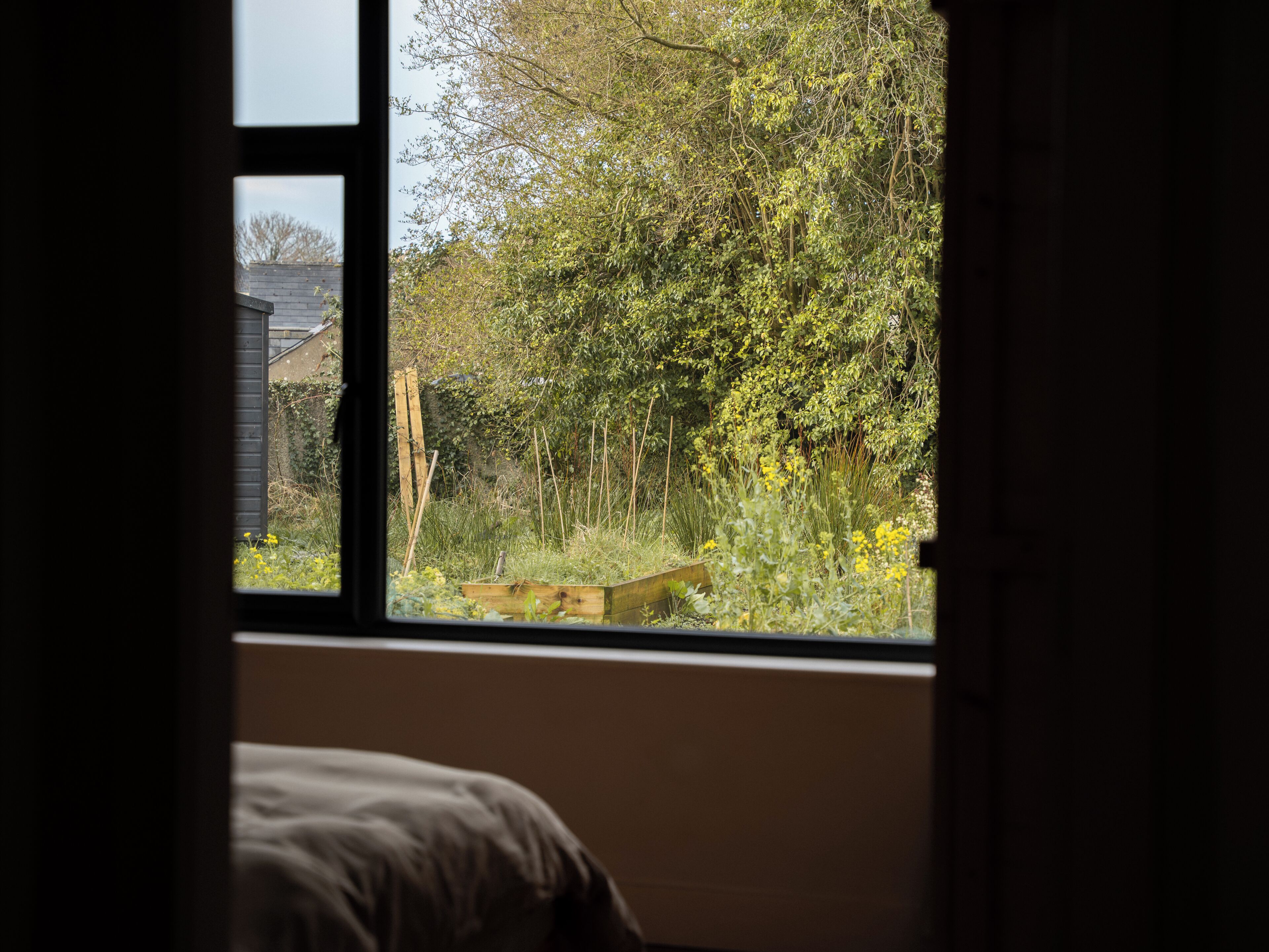 A bedroom with a window overlooking a garden.