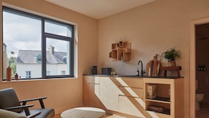 A modern kitchen with a large window, wooden cabinets, and a dining area with a table and chairs.