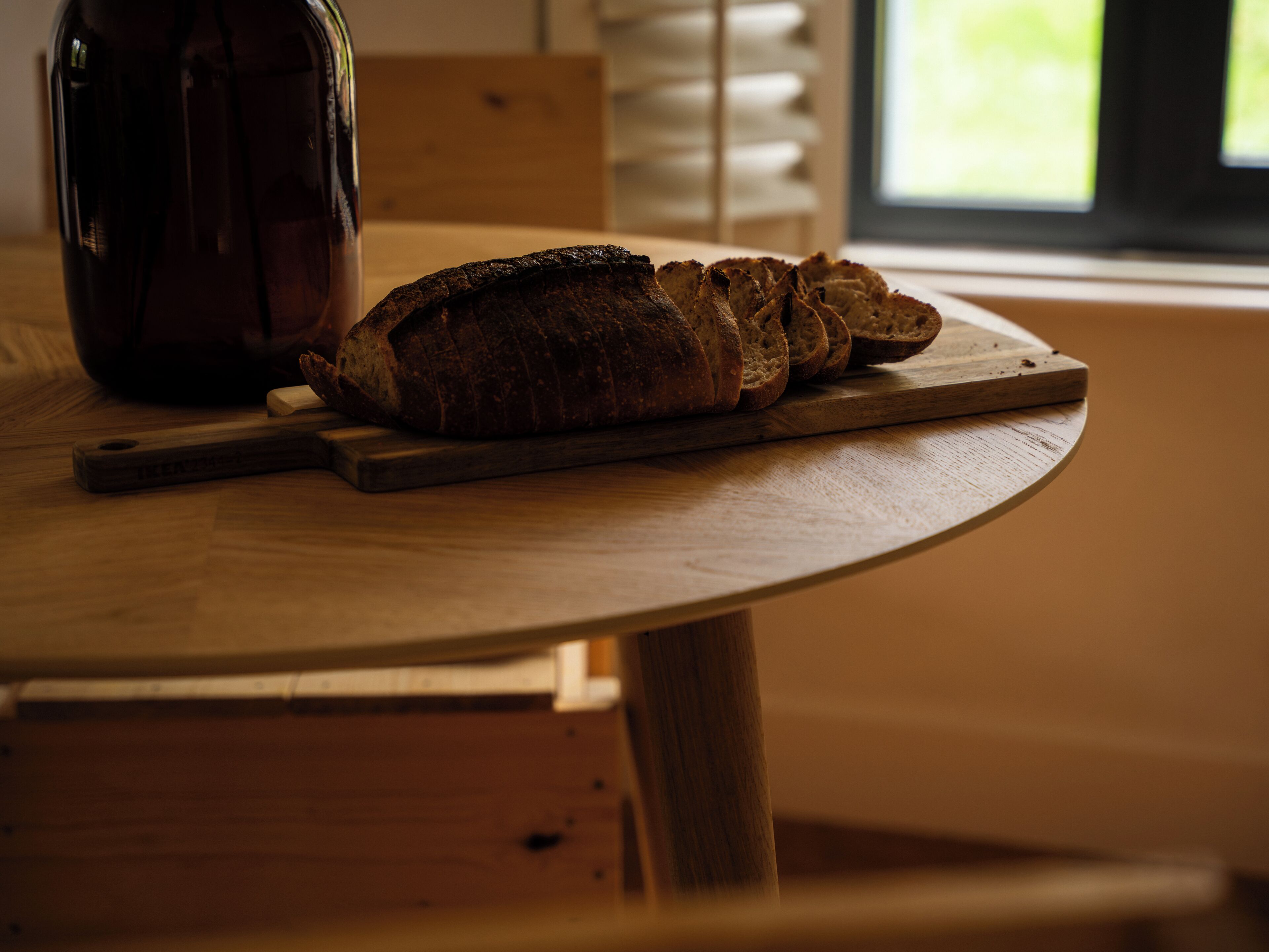 Ein Brot auf einem Holzschnittbrett auf einem runden Tisch.