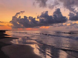 Una playa con olas y un atardecer.