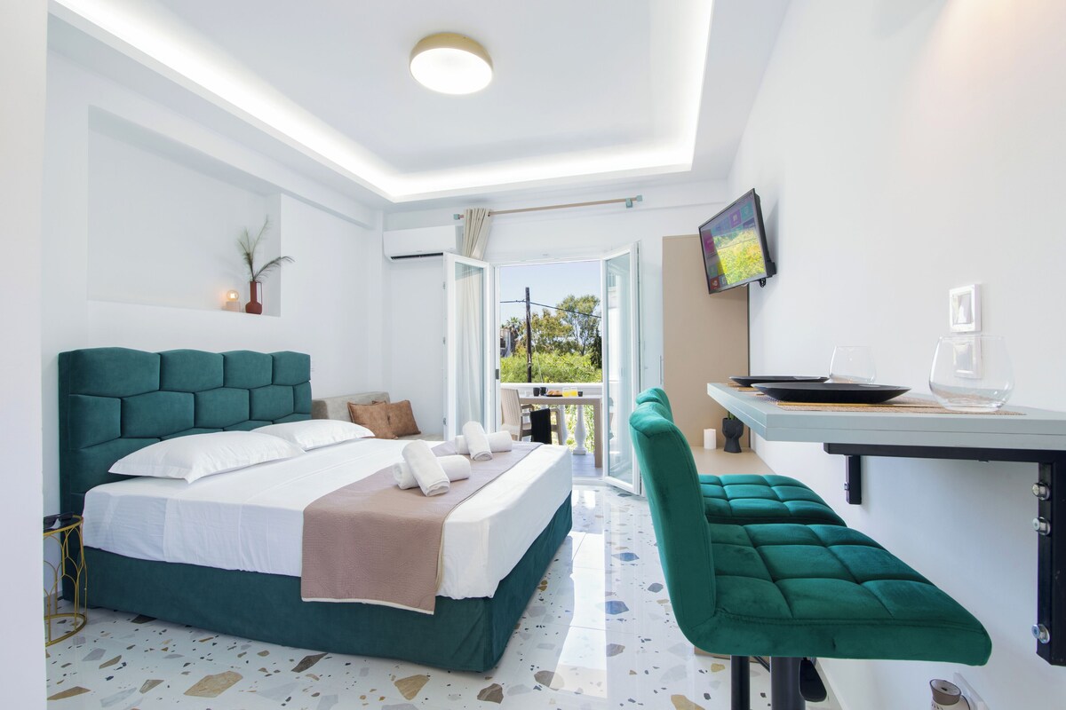 A modern hotel room with a large bed, a desk, and a view of the outdoors.