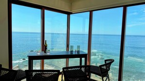 A room with large windows overlooking the ocean, a table with a bottle and glasses, and wicker chairs. - NEW LISTING! OCEANFRONT CORNER TOP FLOOR 2 BEDROOM UNFORGETTABLE VIEWS
 (San Lucas)