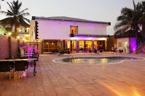 A modern hotel with a pool, outdoor seating, and palm trees. - Continental Hotel by R&K Suites  (Kano)