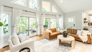 A spacious living room with a high ceiling, large windows, and a cozy seating area with a sofa and armchairs. - Cozy Luxury Treehouse, 10 Min To Asheville, Mountain Views (Swannanoa)