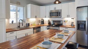A modern kitchen with white cabinets, stainless steel appliances, and a wooden island with seating.