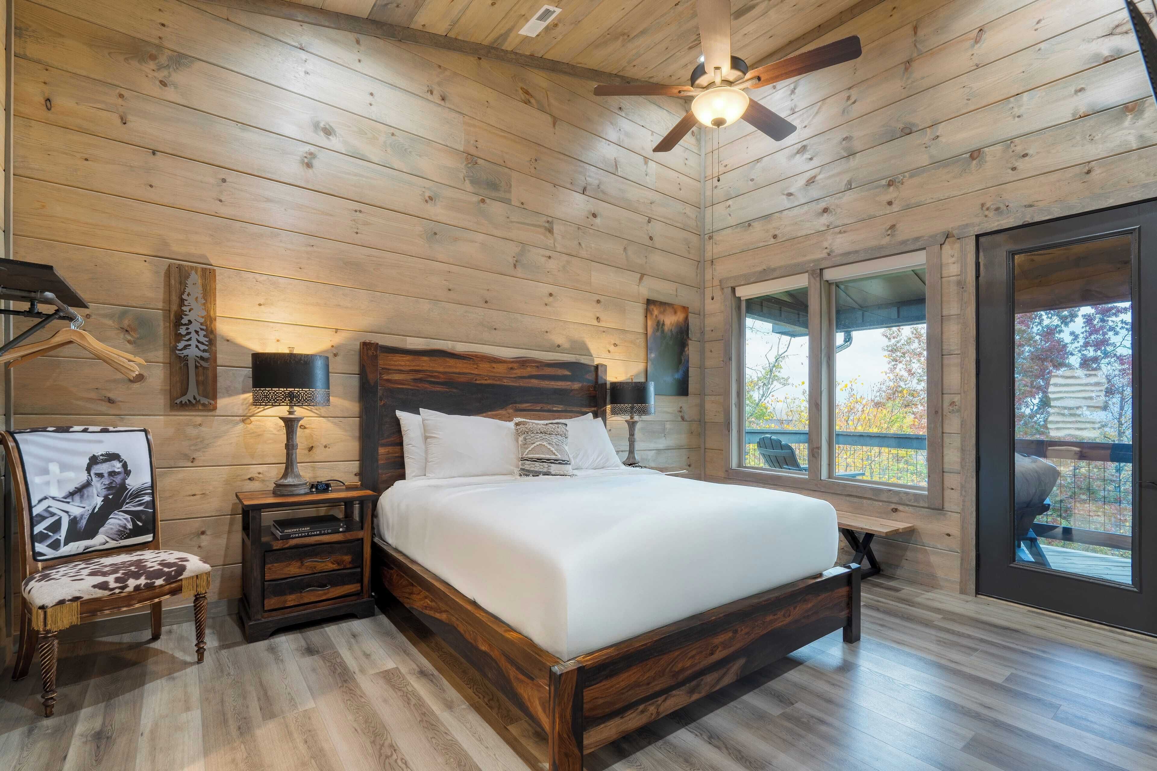 Une chambre à coucher dans un chalet en bois, avec un lit, des tables de chevet, une chaise et une grande fenêtre.