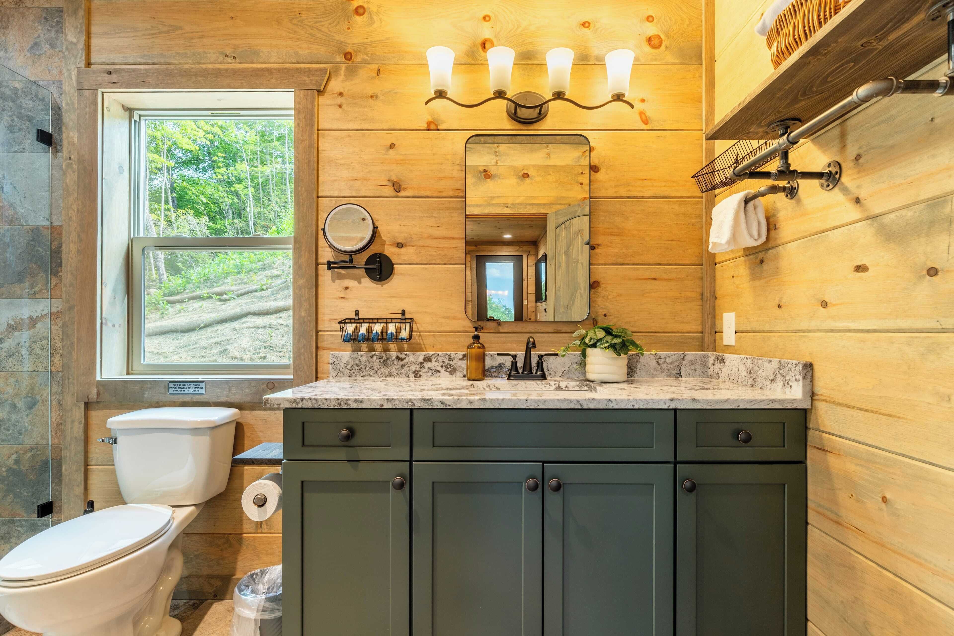 A bathroom with a wooden interior, a window, a sink with a mirror, and a toilet.