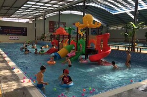 Una piscina interior con diversas estructuras de juegos acuáticos, incluyendo toboganes.