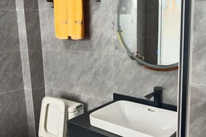 A bathroom with a white sink, a mirror, and a toilet.