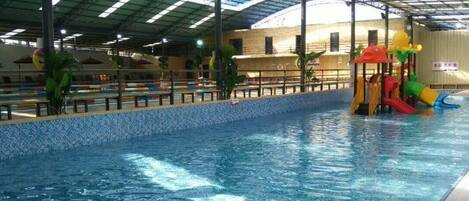 An indoor swimming pool with a slide and a play area.