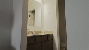 A bathroom with a white sink, dark cabinets, and a mirror with a light fixture above it. - Hotel suite with AC, WiFi, fitness room in welcoming Wilkes-Barre (Wilkes-Barre)