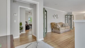 A spacious living room with a wooden floor, a beige sofa, and a white fireplace.
