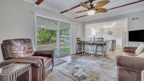 A spacious living room with leather sofas, a glass coffee table, and a ceiling fan.