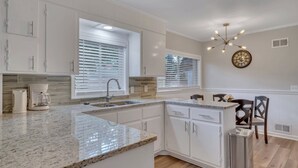 A modern kitchen with white cabinets, granite countertops, and a built-in island.