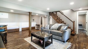 A spacious living room with a sofa, a glass coffee table, and a staircase.