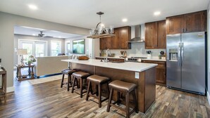 A modern kitchen with wooden cabinets, a stainless steel refrigerator, and a central island with stools.