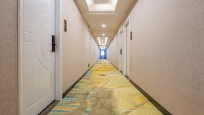 A long, narrow hotel corridor with doors on both sides, a patterned carpet, and recessed lighting on the ceiling. - Shengjia Theme Hotel (Guangzhou Dashi Metro Station) (Guangzhou)