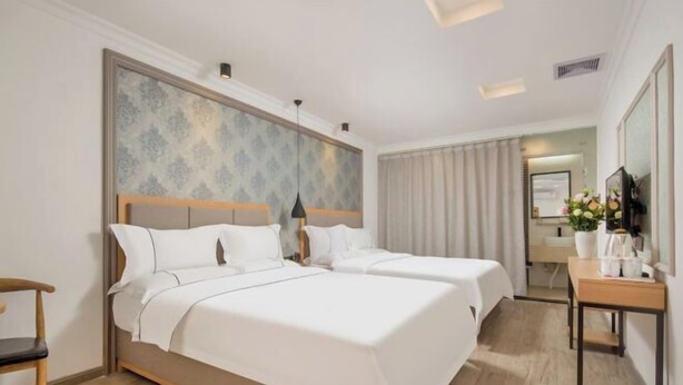 A hotel room with two beds, a desk, a chair, and a mirror. - Shengjia Theme Hotel (Guangzhou Dashi Metro Station) (Guangzhou)