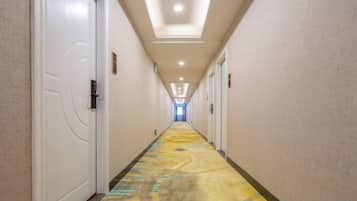 Un pasillo de hotel con puertas a ambos lados, una alfombra estampada e iluminación empotrada en el techo.