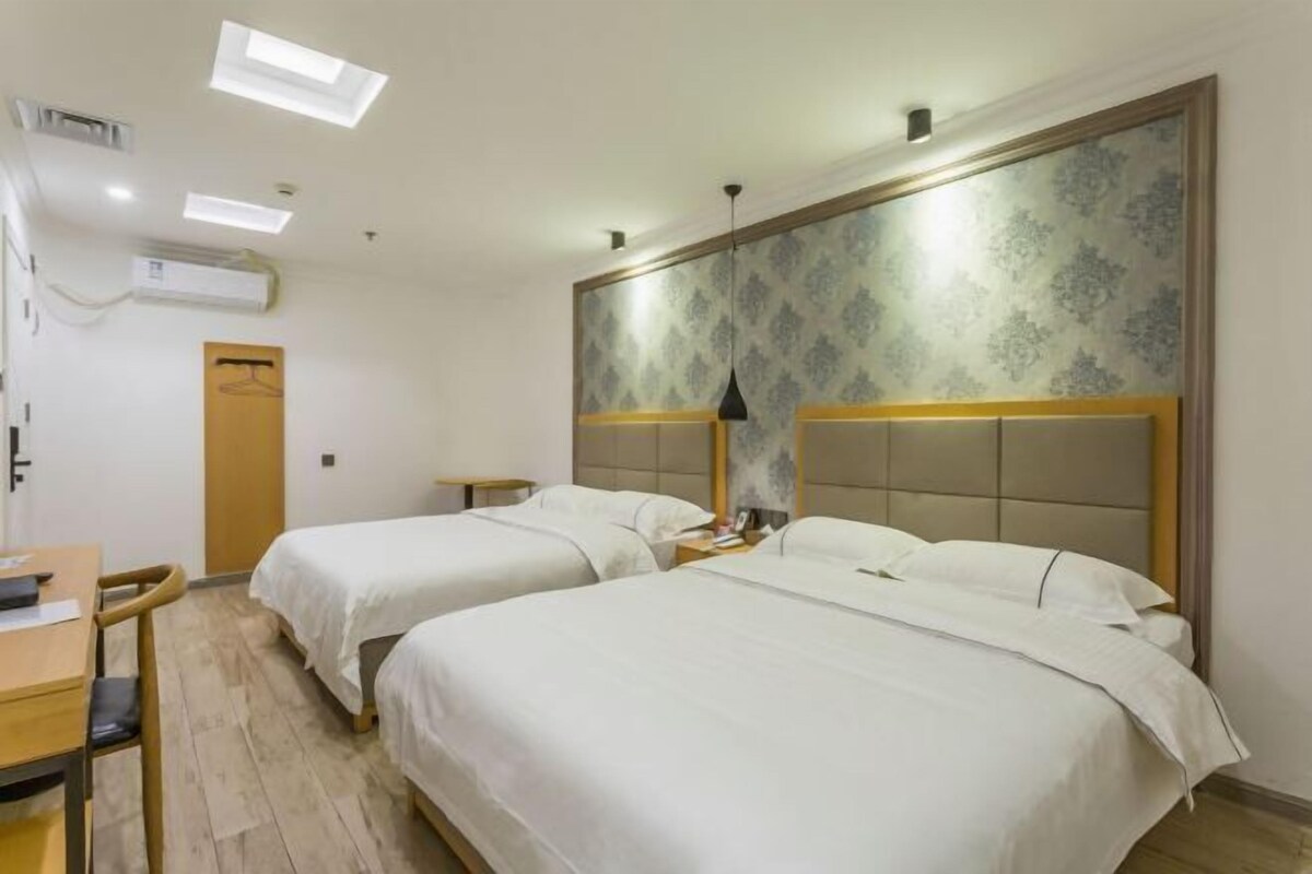 Een hotelkamer met twee bedden, een bureau en een stoel.