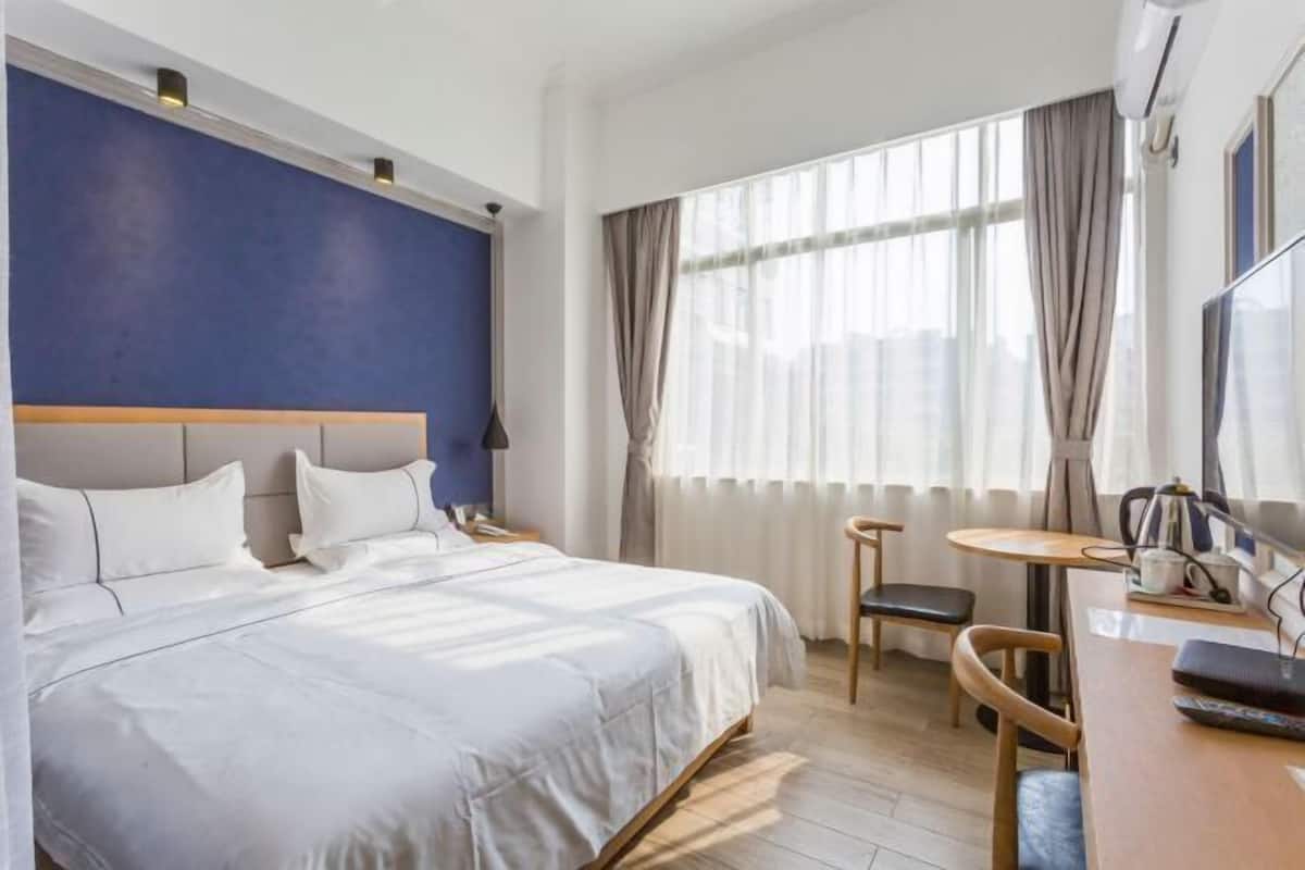 Quarto de hotel com uma cama grande, uma mesa e uma cadeira.