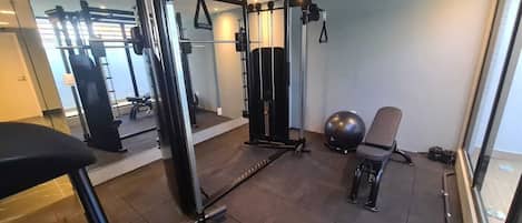 A gym with exercise equipment, a bench, and a chair.