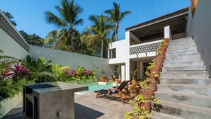 A modern outdoor pool area with a concrete structure, lounge chairs, and a staircase leading to a second floor. - Beautiful luxury villa in the heart of San Pancho, ideal for families and friends. (San Francisco)