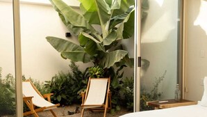 A bedroom with a large bed, a wooden chair, a small table, and a large plant. - Beautiful luxury villa in the heart of San Pancho, ideal for families and friends. (San Francisco)