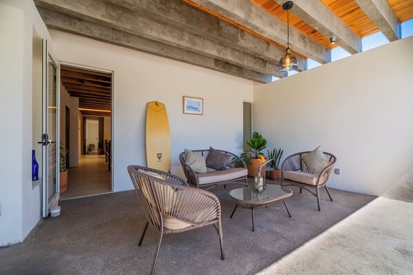 A modern outdoor seating area with wicker furniture, a surfboard, and a potted plant. - A beautiful luxury villa in the heart of San Pancho, ideal for families and friends (San Francisco)