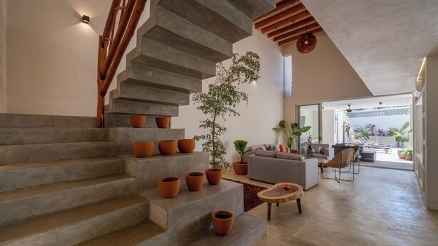 A modern interior with a concrete staircase, a living area with a sofa and coffee table, and a large window offering a view of the outdoors. - Beautiful luxury villa in the heart of San Pancho, ideal for families and friends. (San Francisco)