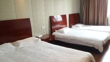 Habitación de hotel con dos camas individuales, cabeceros de madera, una mesita de noche y un ventanal con cortinas.