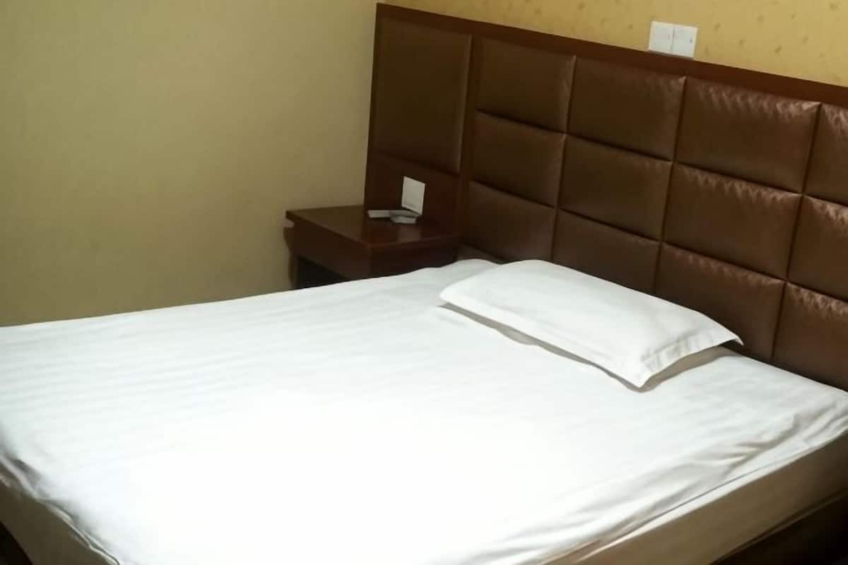 Une chambre d’hôtel avec un lit, une table de chevet et une tête de lit.