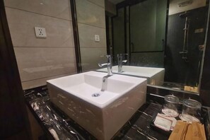 Un baño moderno con un lavamanos grande blanco, un espejo y una encimera negra.