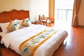 A hotel room with a large bed, a wooden headboard, a small table, a chair, and a view of the outside.