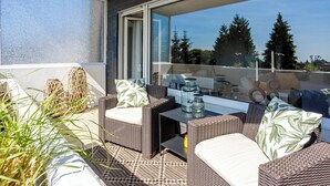 A balcony with wicker furniture, a glass table, and a view of trees and buildings. - Modern apartment with balcony & 2 parking spaces (Odenthal)