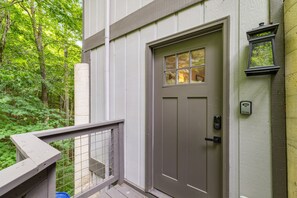 Set amidst lush greenery, this residence features a charming entrance with a door and a small window above it.
